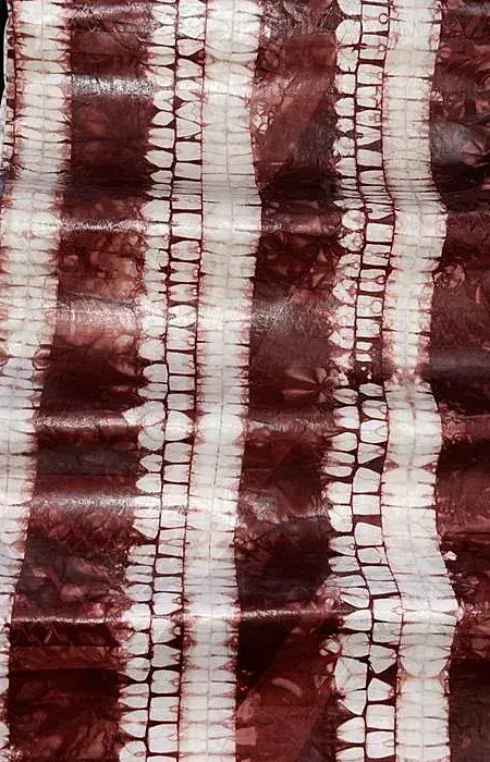 Bazin teinté bordeaux, bandes verticales écrues obtenues par ligature.