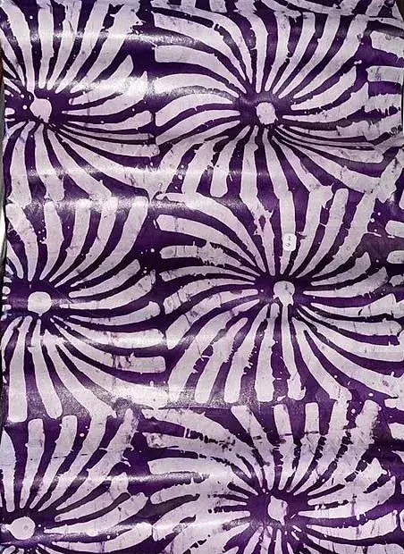 Bazin teinté parme, rosaces claires en spirale sur fond soutenu.