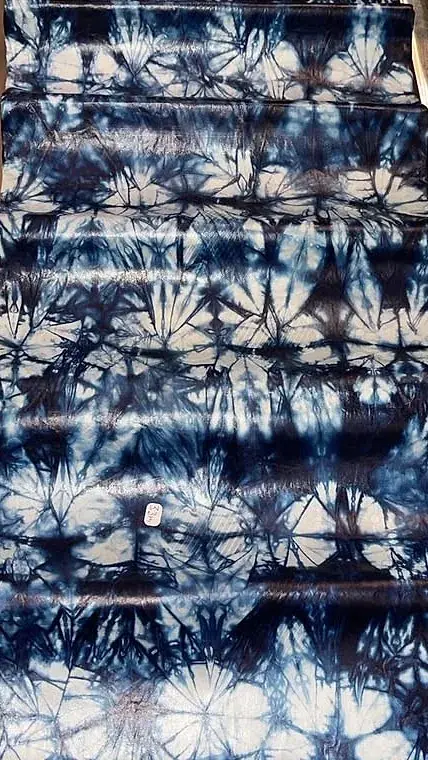 Bazin teinté indigo, rangées de cercles clairs obtenus par ligature.