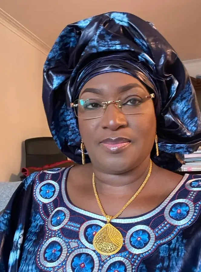 Portrait rapproché d’une femme en foulard et boubou de bazin teinté indigo, encolure brodée.